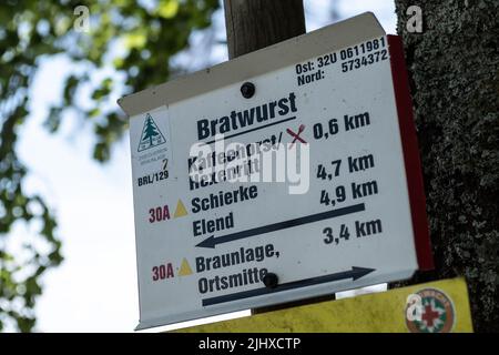 Braunlage, Germany. 20th July, 2022. A signpost with the inscription 'Bratwurst' stands on a hiking trail to the Wurmberg in the Harz mountains. The 'Bratwurst' is a section of a circular hiking trail around the Wurmberg and the name comes from a sharp bend in the trail. Credit: Swen Pförtner/dpa/Alamy Live News Stock Photo