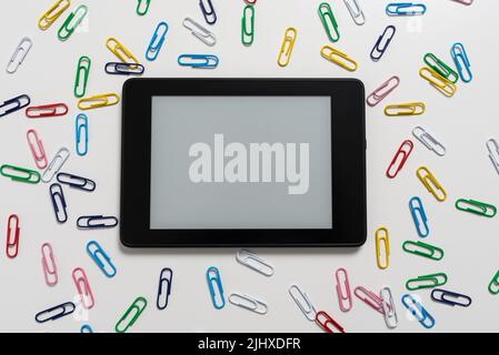 Tablet Screen With Important Message On It Surrounded With Paperclips. Colorful Clips Arranged Around Pad With Crutial Informations. Staples All Over Stock Photo