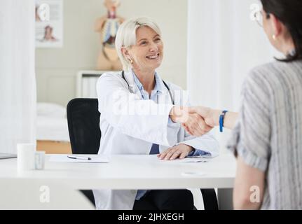 Here for your benefit. a mature female doctor shaking hands with a patient. Stock Photo