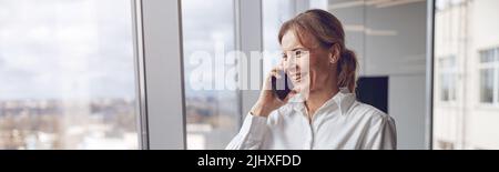Portrait of middle aged woman using mobile phone and making a call while working at office Stock Photo