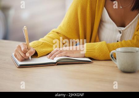 Its all on paper. an unrecognizable businesswoman writing in a notebook at home. Stock Photo