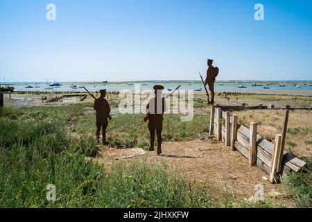 Remembrance, view of three commemorative  'Tommy' figures in silhouette sited on the beach in West Mersea, Mersea Island, Essex, England, UK Stock Photo