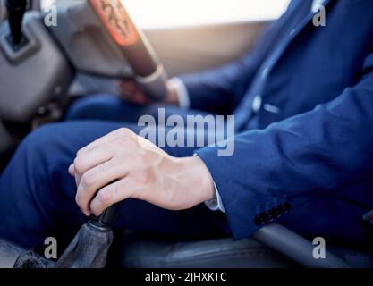 Driving at a safe speed and with caution. Closeup shot of an unidentifiable businessman changing gears while driving a car. Stock Photo