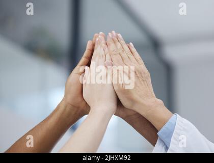 Their support means so much. a group of unrecognizable people giving each other a high five at work. Stock Photo