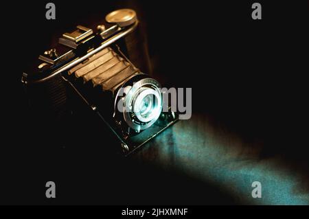 Vintage analog film camera with a bright cold ray of light. Vintage photographic equipment. Stock Photo