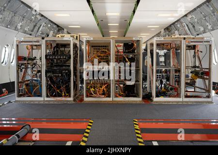 Flight testing equipment in the rear cabin of a Boeing 777X jet airliner, at the Farnborough Airshow, on 20th July 2022, at Farnborough, England. As a result of the fatal accidents of the 737 Max, the 737 fleet was grounded around the world and Boeing is now recovering from a resulting financial downturn. The flight test cabin is configured for computer work stations and cabling which relay data while water ballast transfers weight and centre-of-gravity information to sensors during flight, gathering callibrated performance information before official the aircraft's eventual certification. Stock Photo