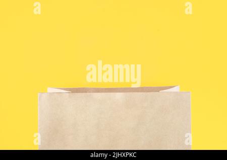 The open brown paper shopping bag on yellow background. Stock Photo