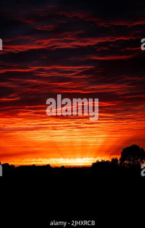 Red sunset over the Dutch countryside. Textured clouds are illuminated orange and red by the already set sun. Stock Photo
