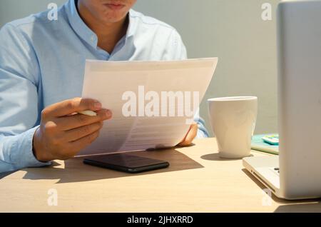 Businessman holding paperwork document finance investment and marketing concept with computer laptop on desk. Stock Photo