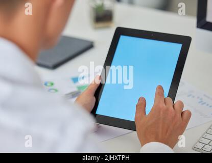 Unknown businessman browsing the internet on an office digital tablet. Mixed race professional sitting alone and scrolling through schedule and social Stock Photo