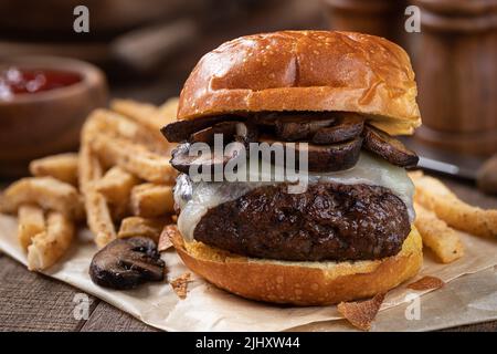 Closeup of cheeseburger with mushrooms on toasted bun with french fries Stock Photo