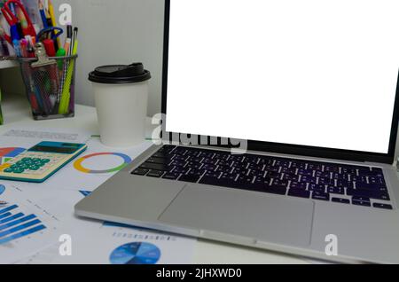 Document graph and chart report financial investment marketing with mock up white screen blank computer laptop on desk business concept. Stock Photo