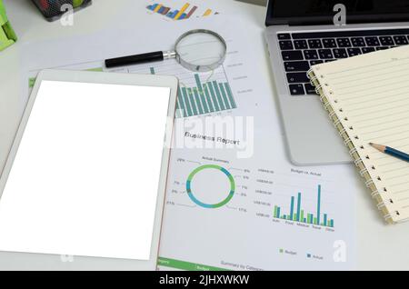 Document graph and chart report financial investment marketing with mock up white screen blank tablet on desk business concept. Stock Photo