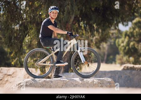 Portrait of a handsome man wearing a helmet and taking a break from cycling on his bicycle outside. Male athlete exercising in a park. Sporty male Stock Photo