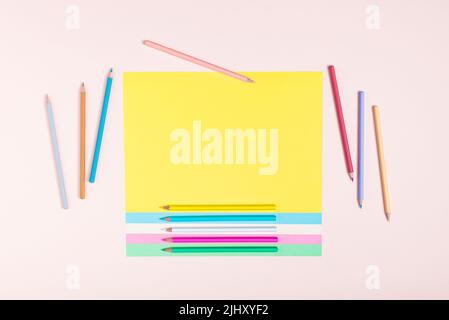 Pencils in pastel colors creatively arranged in a pattern on multicolored papers and a pink background. Back to school concept. Rectangular layout wit Stock Photo