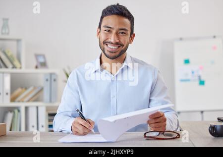 Mixed race cheerful Businessman executive writing notes on paper . Male Hispanic financial advisor smiling and sitting in a office at a startup Stock Photo