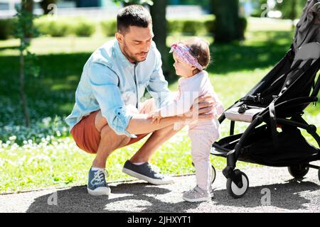 happy father with child in stroller at summer park Stock Photo