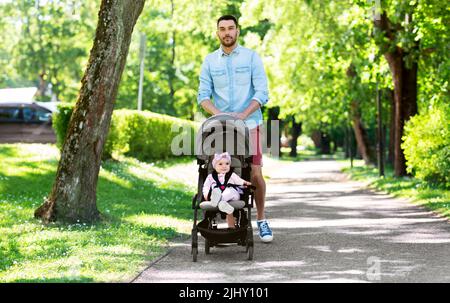 happy father with child in stroller at summer park Stock Photo