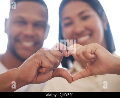 Closeup of mixed race couple making heart shape with hands. Two lovers showing heart sign by joining fingers. Shape of love Stock Photo