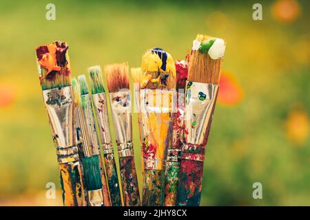 Selective focus on colourful paintbrushes on green nature background Stock Photo