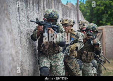 Waimanalo, United States. 18 July, 2022. Malaysian Army soldiers and a U.S. Marine prepare to secure a compound during a simulated urban terrain warfare exercise during the Rim of the Pacific exercises, July 18, 2022 in Bellows Air Force Station, Hawaii. Credit: MCS Leon Vonguyen/U.S. Navy/Alamy Live News Stock Photo