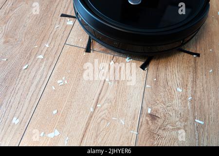 Robotic vacuum cleaner on laminate wood floor smart cleaning technology. Stock Photo