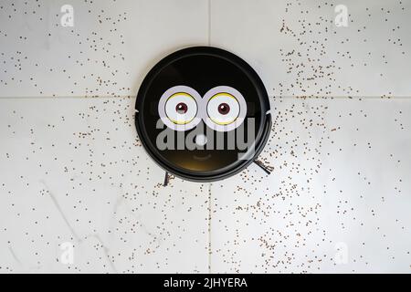 Robotic vacuum cleaner on laminate white tiled floor smart cleaning technology. garbage on the white tiled. top view Stock Photo