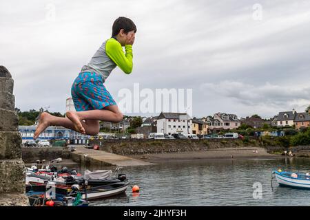 Schull, West Cork, Ireland. 21st July, 2022. On a warm and humid day with temperatures in Schull at 20C, 11 year old Ruaidhra O'Hare from Cork jumps into the water off Schull Pier to cool down. Credit: AG News/Alamy Live News Stock Photo