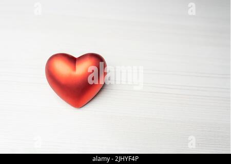 A red heart on a light wooden table. Empty space for test and design. Stock Photo