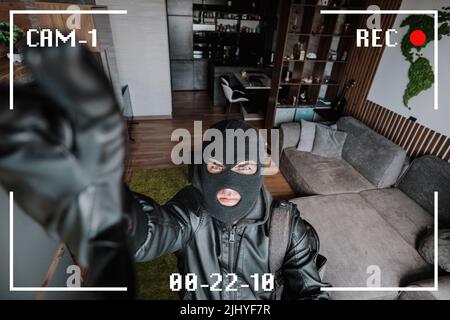 Being Caught. Robber entering house, holding crowbar and looking at CCTV camera, high angle view from above. The robber noticed a security camera. Stock Photo