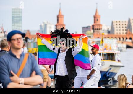Berlin, Germany. 21st July, 2022. Carsten has his picture taken with a Refenbogen flag in front of the Oberbaumbrücke before the start of a Christopher Street Day (CSD) on the Spree. Credit: Christoph Soeder/dpa/Alamy Live News Stock Photo