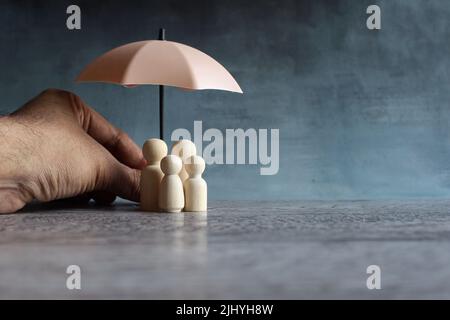 Umbrella and wooden dolls with copy space. Family protection and insurance coverage concept. Stock Photo