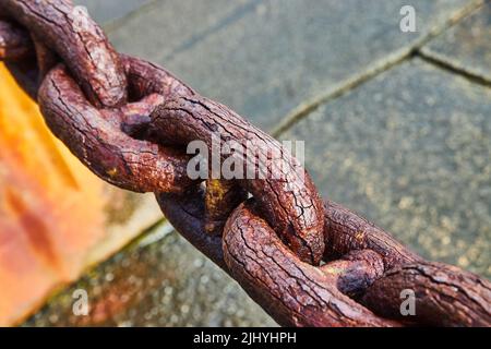 Water erosion on old chain link over concrete Stock Photo