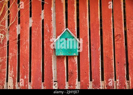 Turquoise birdhouse on faded red barnwood side Stock Photo