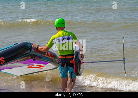 Wing foiling / wing surfing on the North Sea showing wingboarder / wing boarder entering water with foilboard / hydrofoil board and inflatable wing Stock Photo