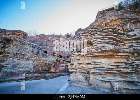 Unique layers of rocks in cliffs by paved path Stock Photo