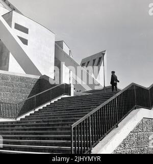 1969, historical, man on exterior stairs, Liverpool Metropolitan Cathedral, Liverpool, England, UK. Designed by Frederick Gibberd - in the modern style of the era - and built in concrete with a portland stone cladding, it was opened (consecrated) in 1967. Conical in shape, the cathedral is supported by a number of concrete trusses or beams. Stock Photo