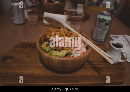 wooden bowl of poke with assorted healthy food and chopsticks on the side Stock Photo