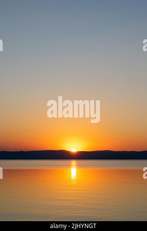 Sunset reflecting on the surface of a lake. Stock Photo