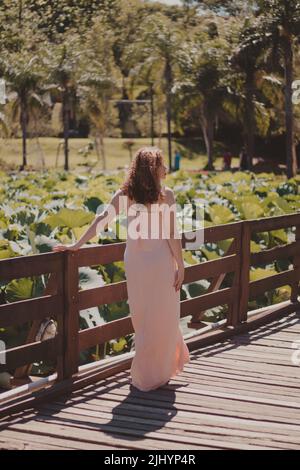 woman in a flowing dress walking through the plant garden Stock Photo