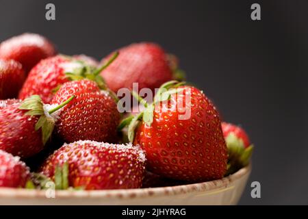 Ripe red strawberries on a plate on a black background, space for text. Stock Photo