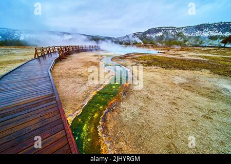 Wet boardwalks of Yellowstone over green alkaline creeks in foggy winter Stock Photo