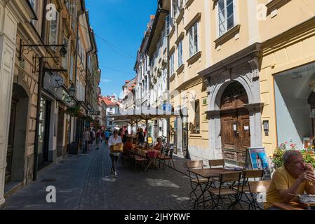 Café - restaurant tables,chairs and sunshades in a narrow street in old part of Ljubljana, Slovenia. Stock Photo