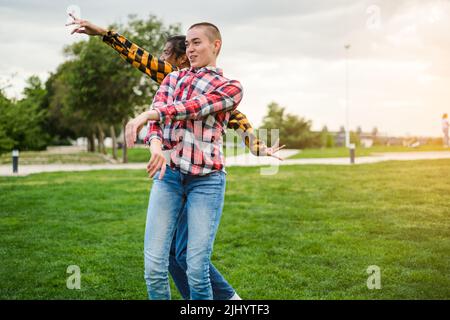 young woman and men in checkered shirts dancing in the park - lifestyle outdoors Stock Photo
