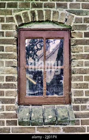 Closeup of an abandoned window covered in spiderwebs from neglect, poverty and economic crisis. Empty, old and dirty residential brick building or Stock Photo