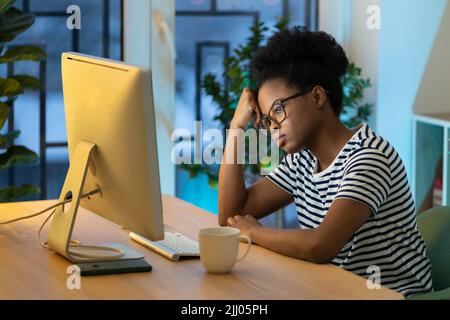 Tired remote employee at home office, unmotivated exhausted african student girl studying online Stock Photo