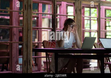 Bored unmotivated woman worker at coworking desk with laptop tired of looking for problem solution Stock Photo