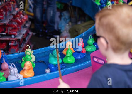 A boy with sunglasses playing a duck fishing mini-game called Hook-a-duck  Stock Photo - Alamy