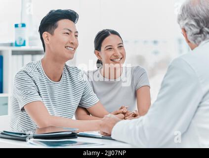 My patients come first, always. a young couple sitting with their doctor during a consultation in the clinic. Stock Photo