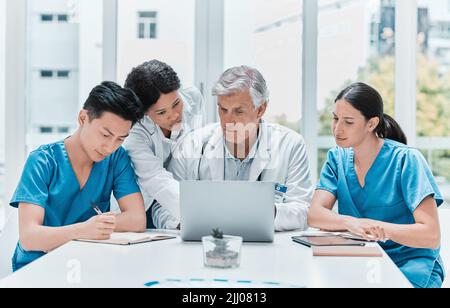 Developing healthcare and medicine as a cooperative science. a group of medical practitioners working together on a laptop in a medical office. Stock Photo